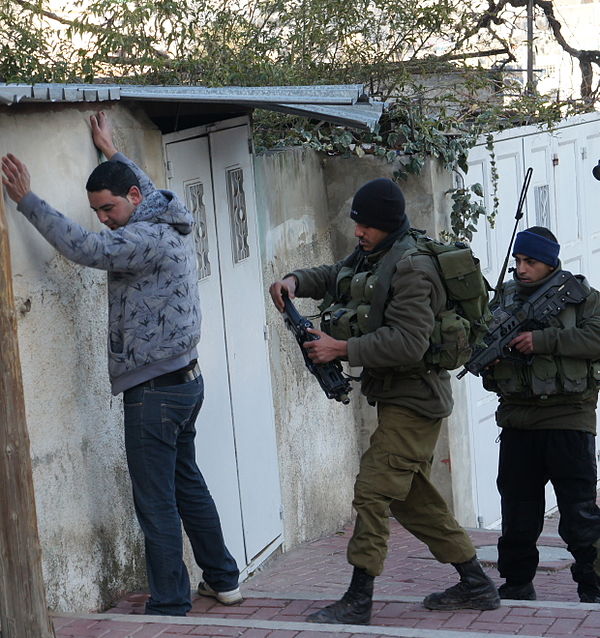 Routine check of a Palestinian man by Israeli soldiers at checkpoint in Hebron